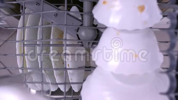 男人手把一个白色的脏杯放在洗碗机的上篮里用厨房用具推着它视频的预览图