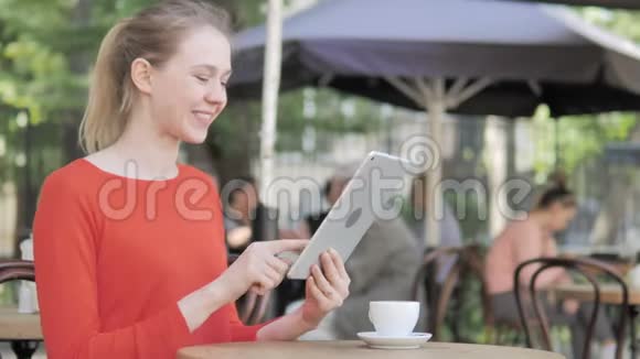 坐在咖啡厅露台上的年轻女性在餐桌上的在线视频聊天视频的预览图
