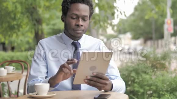 非洲商人使用平板电脑坐在户外咖啡厅视频的预览图