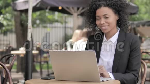 非洲女商人坐在户外咖啡厅的在线视频聊天视频的预览图