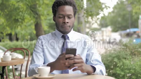 非洲商人使用智能手机坐在户外咖啡厅视频的预览图