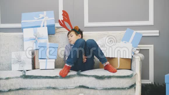 可爱的视频小男孩带着驯鹿头饰睡在沙发上的圣诞老人视频的预览图