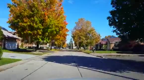 在秋季季节驾驶郊区住宅路落时沿郊区街道的司机视角视频的预览图