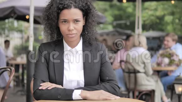 严肃的非洲女商人坐在户外咖啡厅视频的预览图