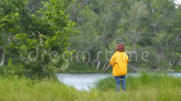 穿着黄色夹克的女人在湖边钓鱼视频的预览图