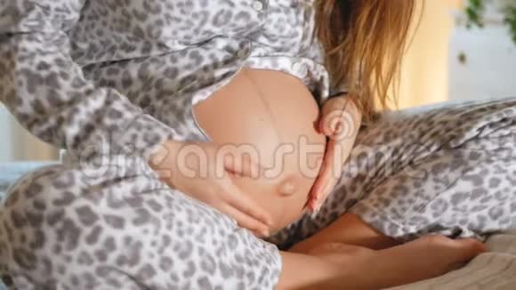 穿着滑稽睡衣的孕妇抚摸着她圆圆的肚子年轻的母亲在等孩子扎肚脐视频的预览图