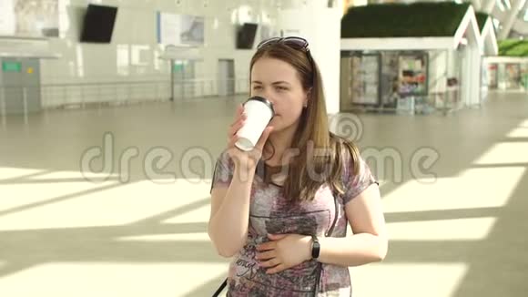 在机场候机大厅拿着行李和咖啡的年轻女子视频的预览图