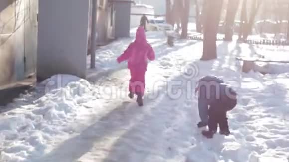 孩子们在阳光明媚的冬天在雪地里散步男孩在雪地里奔跑视频的预览图