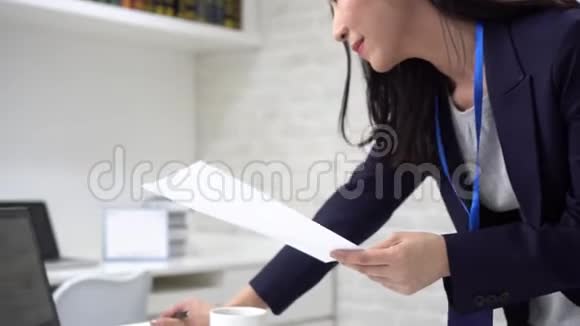 快乐的亚洲女商人在分析办公室统计数据时在笔记本电脑上打字视频的预览图