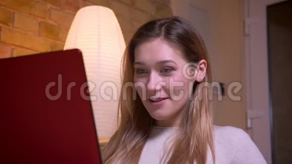 年轻迷人的年轻可爱的黑发女性在笔记本电脑上看电影感到有趣和快乐视频的预览图