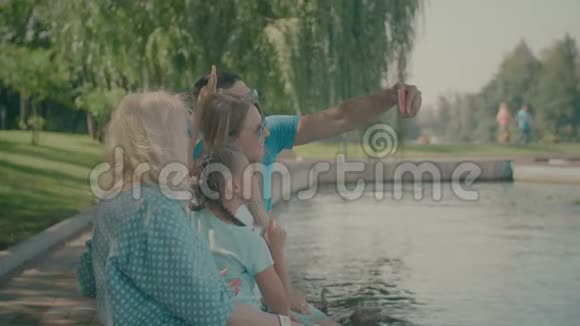 幸福家庭在湖边拍智能手机视频的预览图
