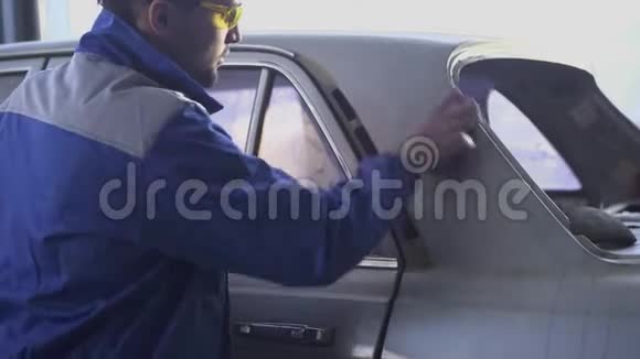 年轻的汽车专家用特殊的眼镜和统一的现代汽车服务抛光汽车视频的预览图