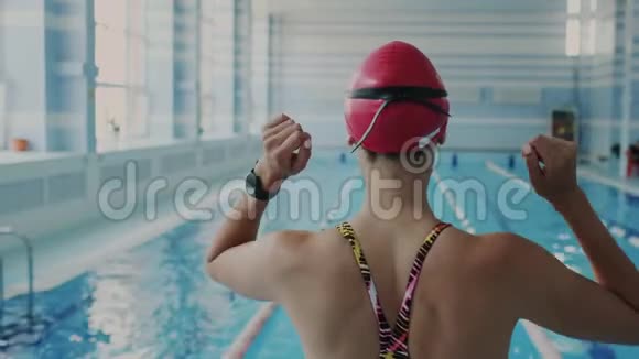 一个苗条又健康的女孩在游泳前会使她的肌肉和变暖她向前倾把手臂举到她的上方视频的预览图