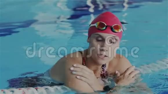 太慢了年轻的女性业余游泳运动员在游泳池道上放松她恢复了呼吸看着里面视频的预览图
