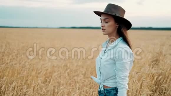 日落时穿着短裤和帽子穿过麦田的漂亮女孩自由概念日落时的麦田现代农业视频的预览图