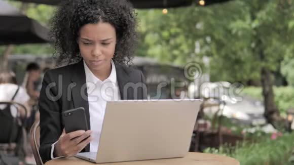 非洲女人坐在户外咖啡厅打电话视频的预览图