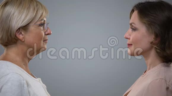 年轻女性和年长女性互相看着灰色的背景衰老的倒影视频的预览图