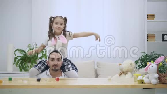 幸福快乐的女儿正坐在父亲肩膀上跳舞父亲坐在木桌下视频的预览图