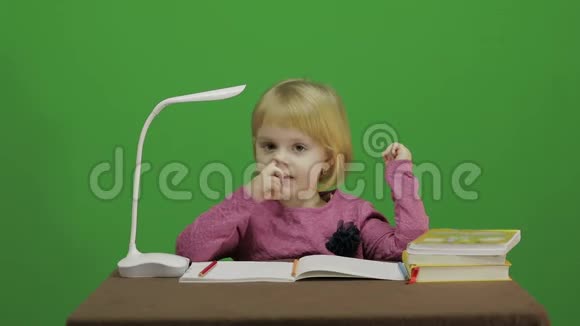 女孩坐在桌子旁抠鼻子课堂中的教育过程快乐的三岁女孩可爱的女孩视频的预览图