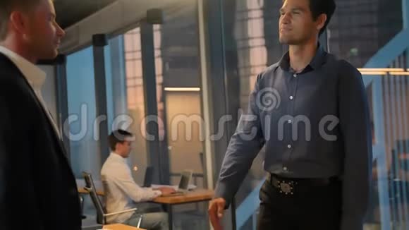 两位企业家用巨大的窗户在现代商务办公室里握手视频的预览图