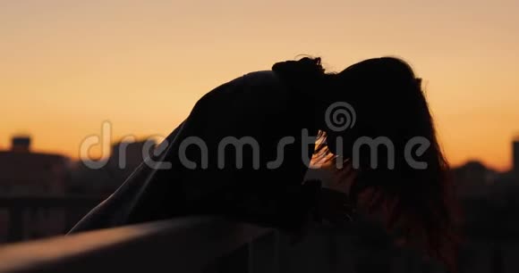 女人的剪影在城市的日落时分把头发乱扔视频的预览图
