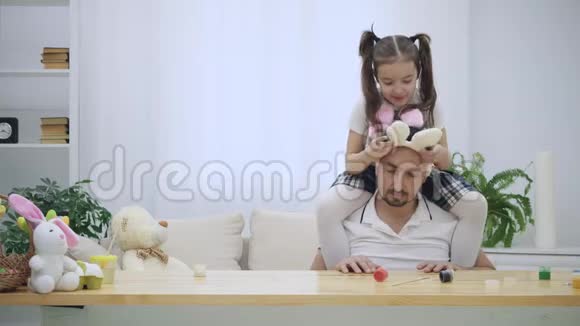 幸福快乐的女儿正坐在父亲肩膀上跳舞父亲坐在木桌旁视频的预览图