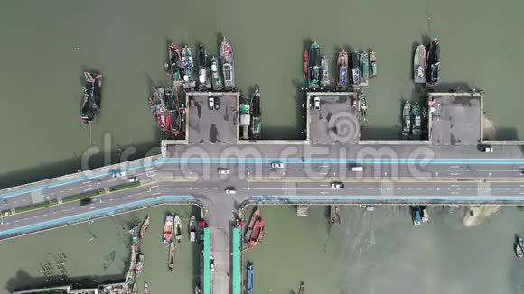 高空俯视海外高速公路有汽车驾驶和渔船靠近海港的海水视频的预览图