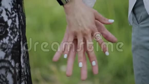 年轻的恋人牵着手沿着夏天的公园散步视频的预览图