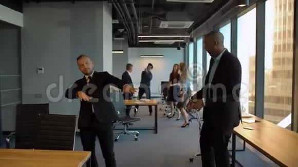 在同事办公室跳舞的白人和非洲裔雇员视频的预览图