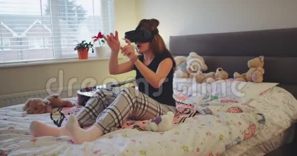 有魅力的少女利用虚拟现实玩一些虚拟游戏她穿着睡衣在房间里视频的预览图