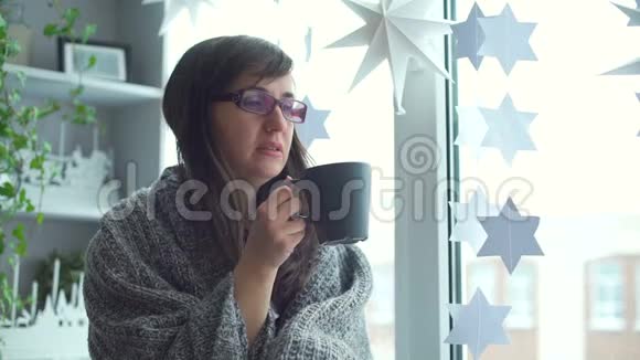 女人裹着格子在窗台上喝茶视频的预览图