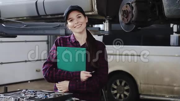 一个戴着黑色帽子和格子衬衫的女孩一个汽车修理工拿着文件在拆卸的汽车前面展示了一个视频的预览图