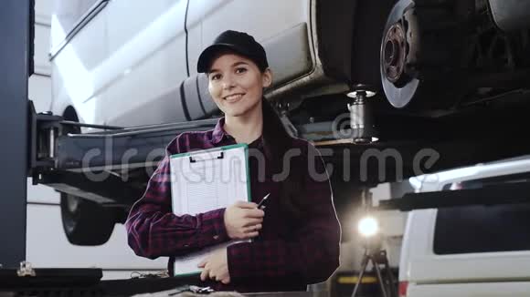 一个女孩的肖像一个穿着格子衬衫的汽车修理工和一顶黑色帽子在一家服务站的一辆汽车前面有一个女孩的肖像视频的预览图