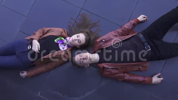 可爱的男人和女孩躺在黑暗的地板上唱歌他们穿着浅棕色的夹克视频的预览图