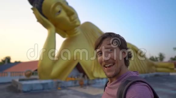 一位年轻的旅行者带着一尊躺着的佛像参观了沃特斯里松棘寺的慢镜头视频的预览图