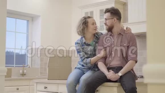 在新公寓的厨房里一对英俊的大胡子男人和一对可爱的女人坐在桌子上家庭讨论计划视频的预览图