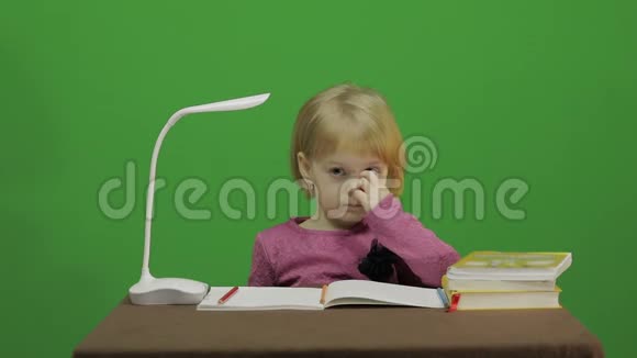 女孩坐在桌子旁抠鼻子课堂中的教育过程快乐的三岁女孩视频的预览图
