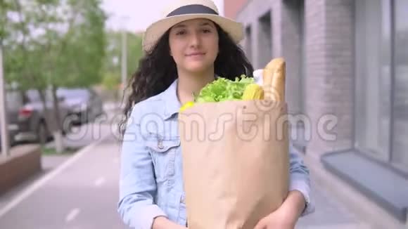 年轻漂亮的女人穿着牛仔夹克和帽子带着一个购物袋4K视频的预览图