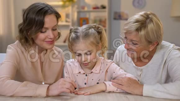 可爱的妈妈给女儿涂粉色的指甲油和家人在一起视频的预览图