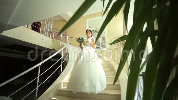 一位漂亮的新娘穿着花边连衣裙站在大台阶上视频的预览图