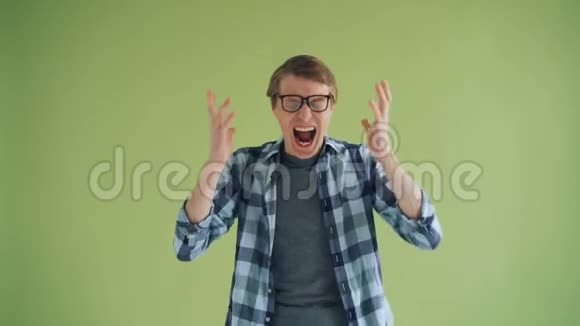 愤怒的人戴眼镜的帅哥在绿色背景上大喊大叫的肖像视频的预览图