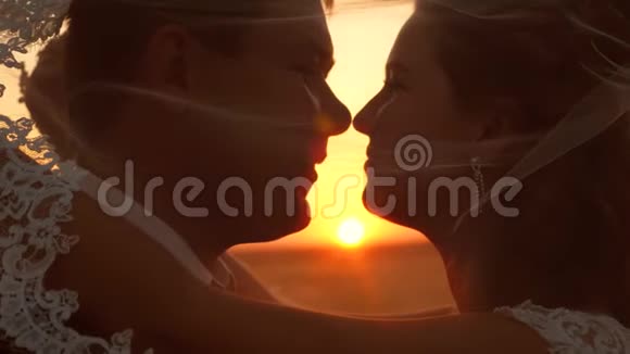 恋爱中的浪漫情侣在日落时接吻幸福家庭的概念新娘和新郎在日落时亲吻和拥抱关闭视频的预览图