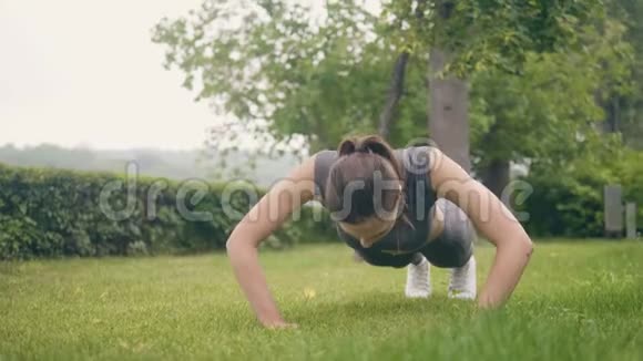 夏季公园户外训练时做俯卧撑运动的健身女孩视频的预览图