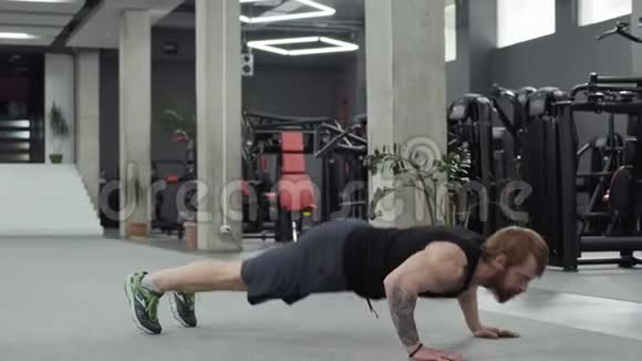 肌肉胡须男在健身房做俯卧撑男子在健身房做加强锻炼视频的预览图