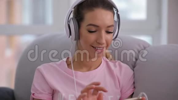 坐在家里舒适的沙发上听音乐的女人视频的预览图