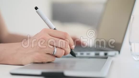 年轻的白人女性设计师使用平面笔平板电脑在笔记本电脑上工作视频的预览图