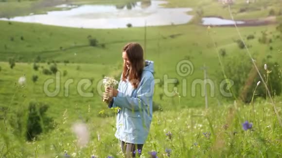 年轻开朗的女人带着鲜花走在田野里视频的预览图