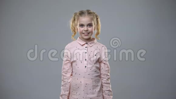 微笑的小女孩手里拿着灰色背景的彩色购物袋礼物视频的预览图