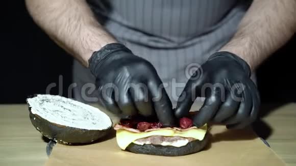 厨师的双手烹饪一个美味的黑汉堡与烟熏培根和樱桃视频的预览图