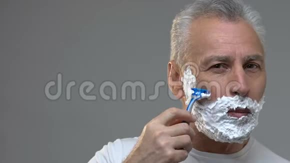 一位英俊的老人专心地刮胡子早晨的卫生程序视频的预览图